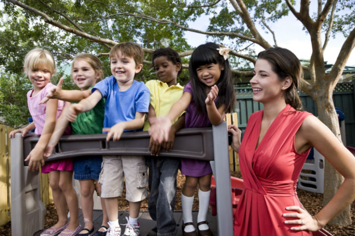 A group of children and adults standing on top of a wooden fence.